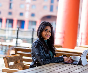 Similing student sitting with cup of coffee outside a cafe